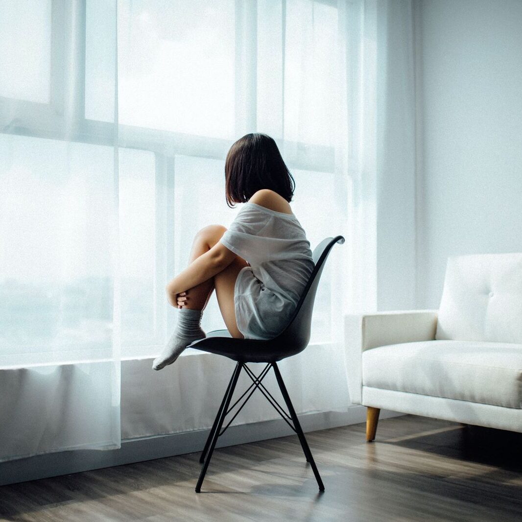 woman siting besides a window